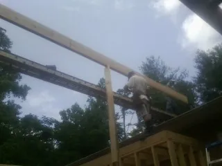 Carpenter setting a ridge beam over a new addition frame — Ice Dam Removal by Roofing Brothers in Vanceboro
