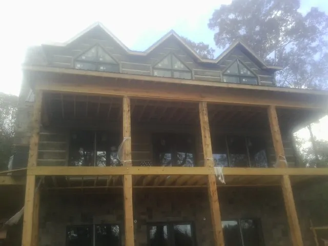 Dormers and porch framing on a large log home under construction — Roof Coating work by our crew in Vanceboro