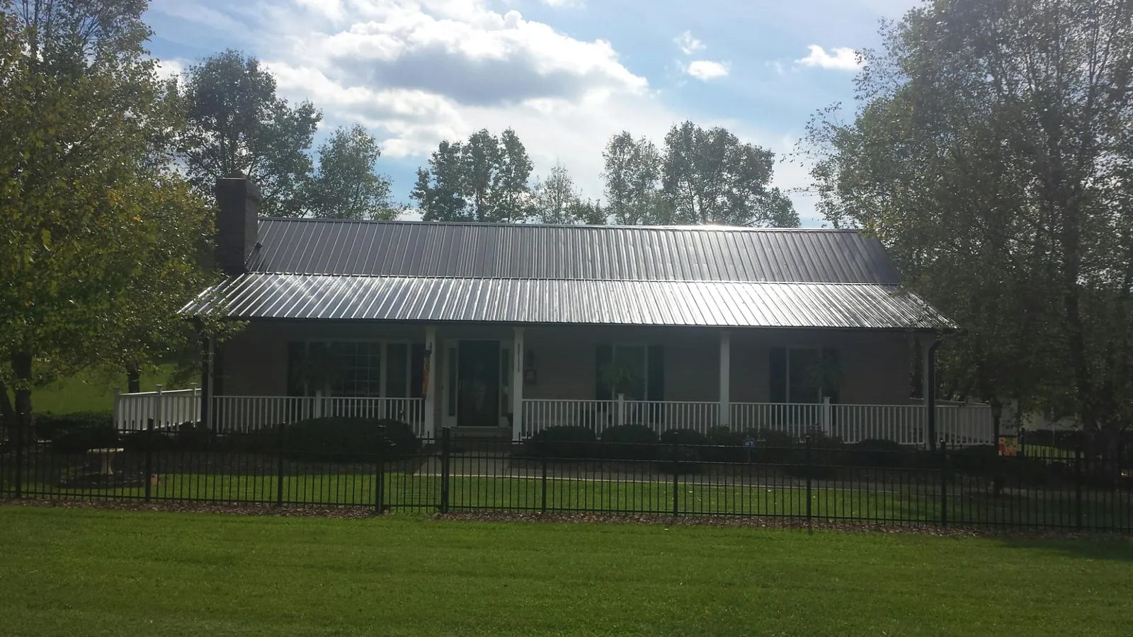 Gray metal roof on a brick ranch with a full width front porch — Gutter Guard Installation work by our crew in Vanceboro