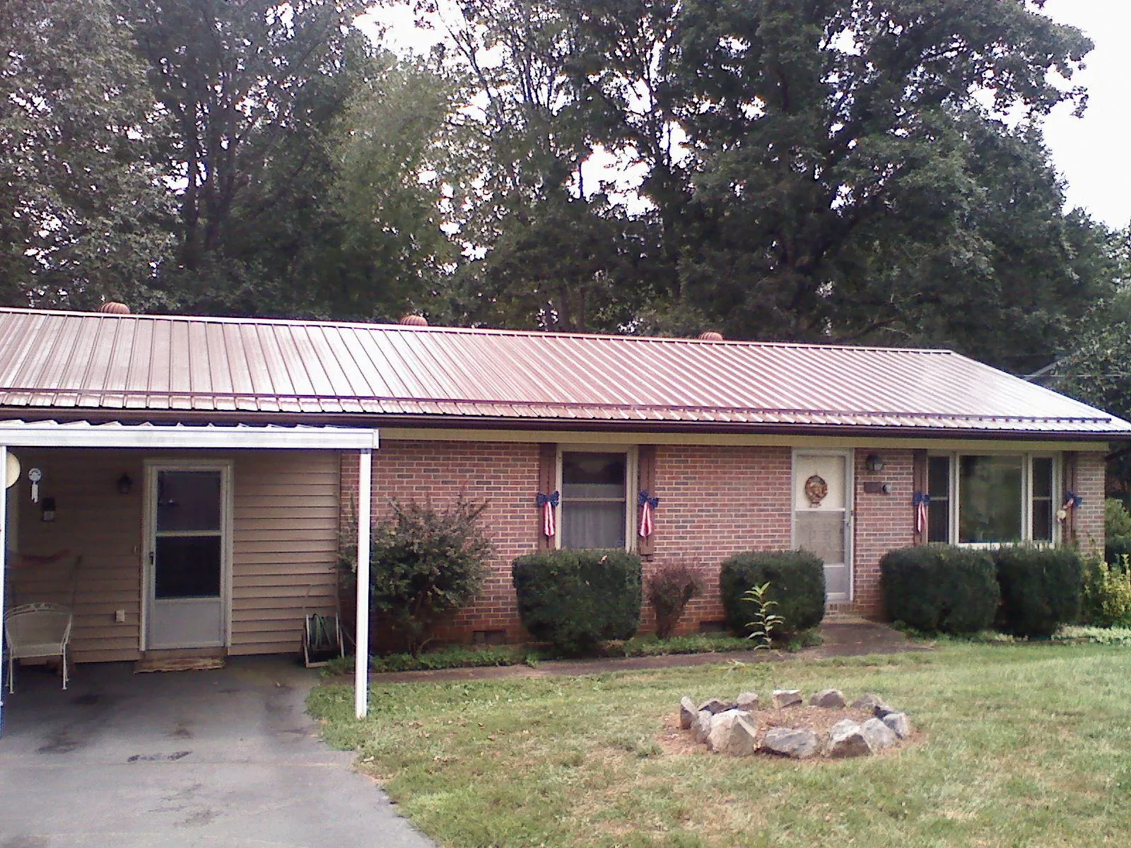 Bronze metal roof and carport on a brick ranch home — Roof Repair work by our crew in Vanceboro